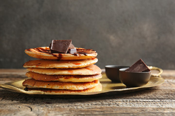 Tray with tasty pancakes and chocolate on wooden table