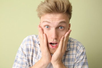 Shocked young man on color background