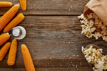 top view of delicious popcorn and corn with salt on wooden background