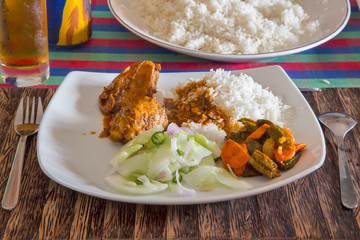   A plate of chicken, rice and vegetables is on the table.
