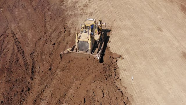 Bulldozer pushing large amount of fresh soil, Aerial follow footage.
