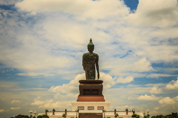 Standing buddha for worship in Phutthamonthon Park with sunset sky and reflective light,beautiful background