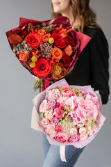 Two Beautiful bouquets of mixed flowers in womans hands. the work of the florist at a flower shop. Fresh cut flower. Red and pink color