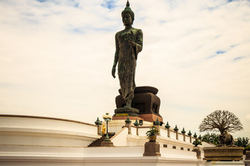 Standing buddha for worship in Phutthamonthon Park with sunset sky and reflective light,beautiful background