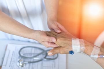 Obraz premium Geriatric doctor or geriatrician concept. Doctor physician hand on happy elderly senior patient to comfort in hospital examination room or hospice nursing home or wellbeing county.