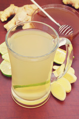 Glass of ginger tea with lime and honey on table