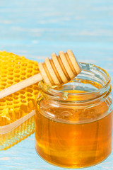 Honey on the background of honeycomb. Honey in a glass jar and honeycomb