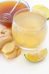 Ginger tea glass, lime and honey on white table close up