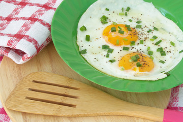 Fried eggs with onion and pepper in green plate