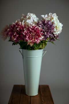 Silk flowers in a tall metal vase