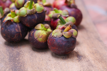 Fresh red and purple mangosteen on wood table. Queen of fruit, good for Anti-anging. Asian local Thai fruit with white fruit after peeling hard shell.