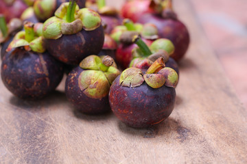 Obraz premium Fresh red and purple mangosteen on wood table. Queen of fruit, good for Anti-anging. Asian local Thai fruit with white fruit after peeling hard shell.