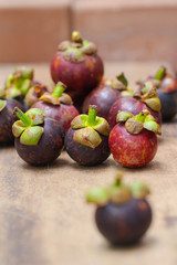 Fresh red and purple mangosteen on wood table. Queen of fruit, good for Anti-anging. Asian local Thai fruit with white fruit after peeling hard shell.
