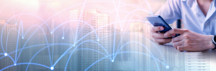 Double exposure image of man in casual shirt holding phone in hand and using smartphone with blur building city, futuristic connection line. Concept of Technology, modernlife and Internet of things.