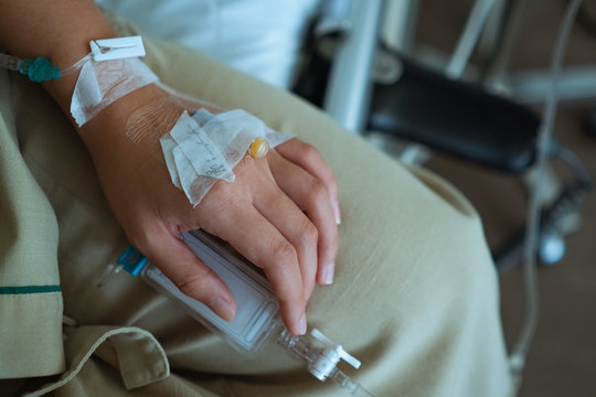 close up hand of patient with medical drip or IV drip in hospital ward, healthcare medical concept - image