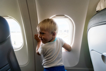 Happy one year old baby boy next to airplain's window