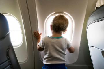 A year old baby boy looking through airplain's window