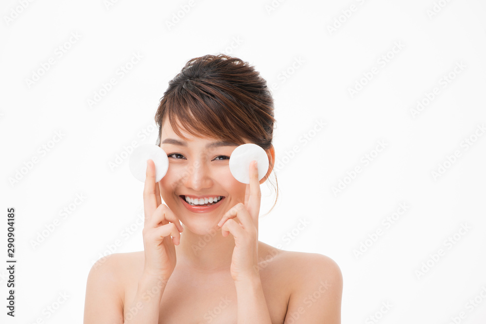 Wall mural beautiful young woman cleaning her face with cotton