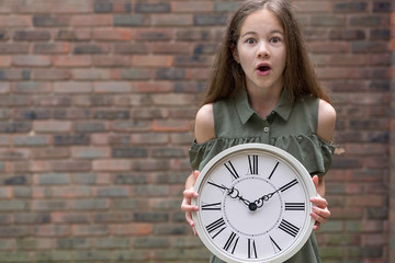 Worried little girl with clock, copy space. Being late, time is the most precious resource concept