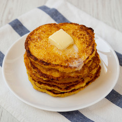 Homemade corn meal Johnny cakes with butter on a white plate, side view. Closeup.