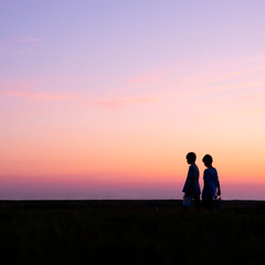 Fototapeta na wymiar silhouette of two boys against colorful sunset