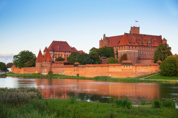 Naklejka na ściany i meble Malbork castle over the Nogat river at sunset, Poland