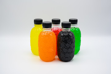 Plastic bottles of water of various colors arranged on a white background.