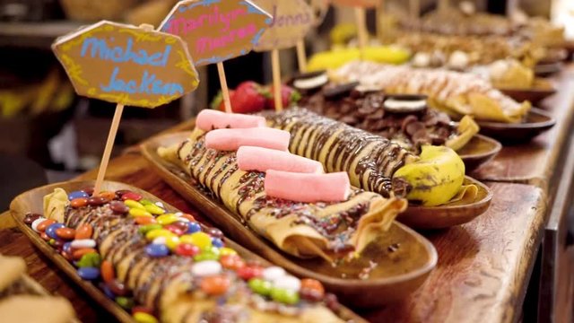 Various colorful cr&ecirc;pes lie on wooden counter