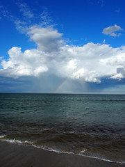 Regenbogen über dem Meer: Aufziehende Regenwolke