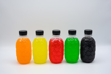 Plastic bottles of water of various colors arranged on a white background.