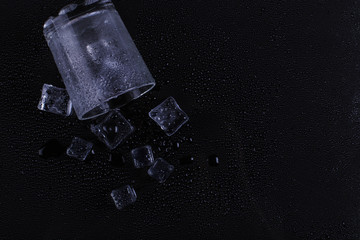 A foggy inverted glass and ice lie on a black background, cold condensate.