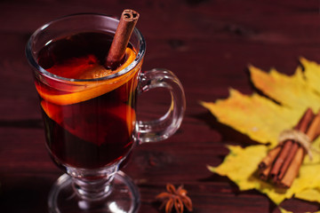 Glass of mulled wine on a wooden table with cinnamon.
