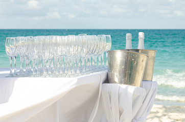 Table set with champagne and glasses and ice bucket on a beach for a destination wedding.