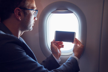 Man using cellphone to take photos through the airplane window.