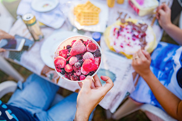 People making a picnic with sweet waffle and pancaces in the garden.