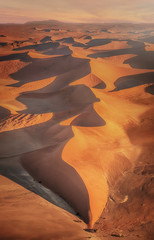 Vertical, aerial shot of sand dunes in the Namib Desert at sunset.