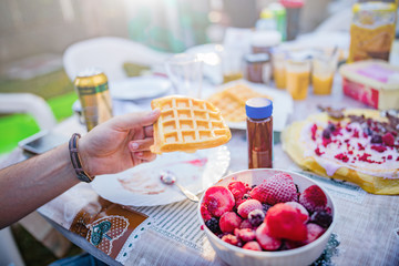People making a picnic with sweet waffle and pancaces in the garden.