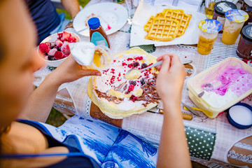 People making a picnic with sweet waffle and pancaces in the garden.