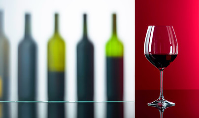 Bottles and glass of red wine on a black reflective background.