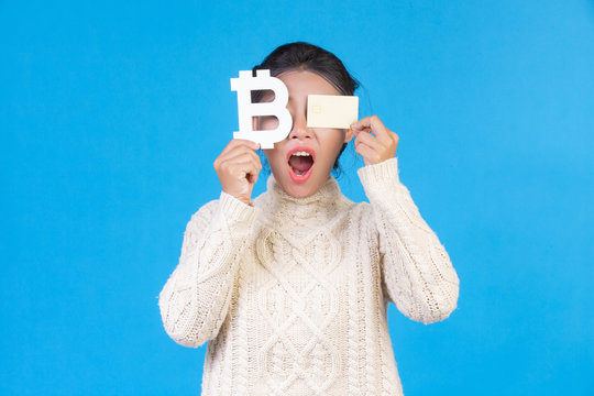 Beautiful women wearing a new long-sleeved white carpet, holding the symbol of Thai baht and a gold credit card on a blue background. Trading concept.