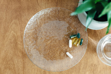 Dietary supplements, biologically active additives.Omega 3, spirulina, chlorophyll,magnesium capsules and glass of water on wooden table. Morning vitamin pills.  Health support. Copy space