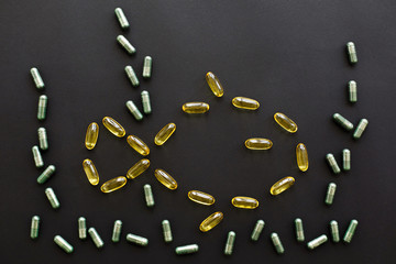 Dietary supplements. Omega 3 capsules in fish shape and spirulina pills as algae seaweed on black dark background. Flat lay. Health support and treatment. Biologically active additives