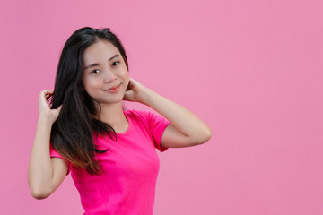 Cute white Asian woman poses herself with a pink hair on a pink background.