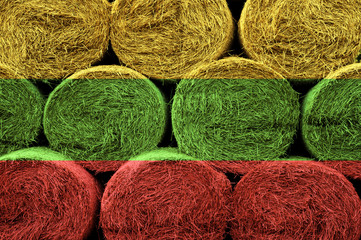 Lithuania flag on the surface of a stack of hay rolls.