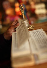 Close-up of a praying Buddhist monks hand with book in a puja in Lamayuru monastery.