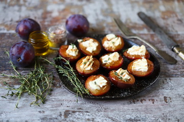 Baked plums with feta cheese and thyme. Keto friendly. Selective focus. Macro.
