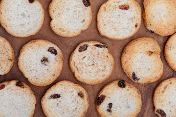 Mini round toasts of bread with raisins. Texture. On dark wood background.