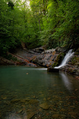 Obraz premium waterfall in the forest. Waterfall flows into a small lake.