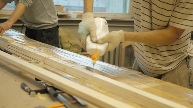 The master in the carpentry workshop glues the boards with special glue before pressing