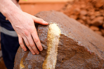 Close up picture of scientist geologist hands inspecting exploration colorful of iron ore rock on...